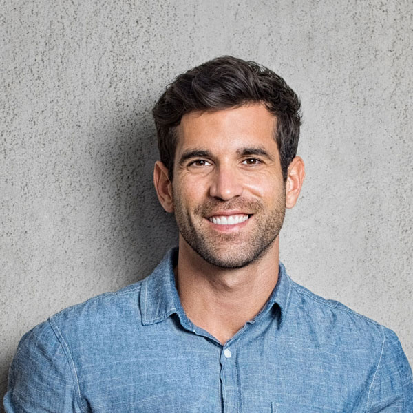 man smiling and standing against wall