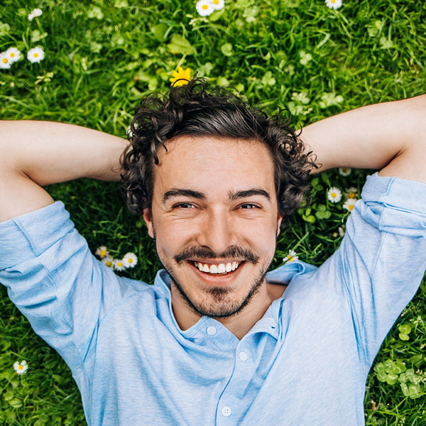 man smiling and laying on the grass