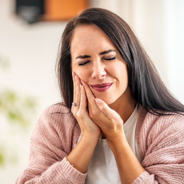 woman holding face and feeling tooth pain